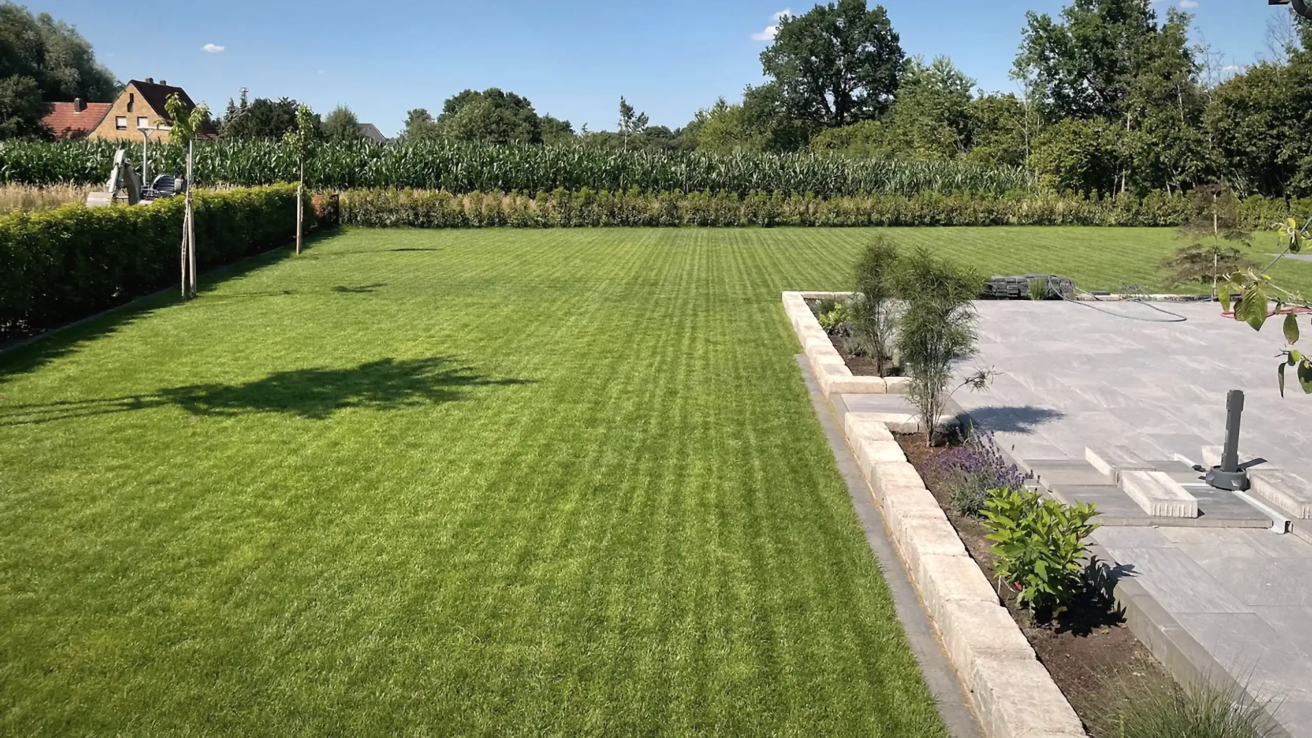Weitläufige, frisch angelegte Gartenanlage mit gepflegtem Rasen und Natursteinterrasse von Fortkamp in Ahaus