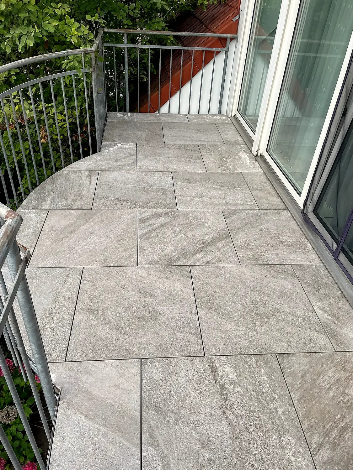Sanierter Balkon mit großformatigem Plattenbelag und geschwungener Kante