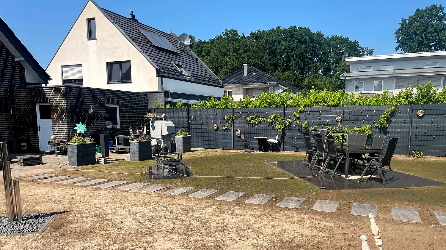 Blick ueber die Gartenanlage mit Sitzgruppe und Rankwand