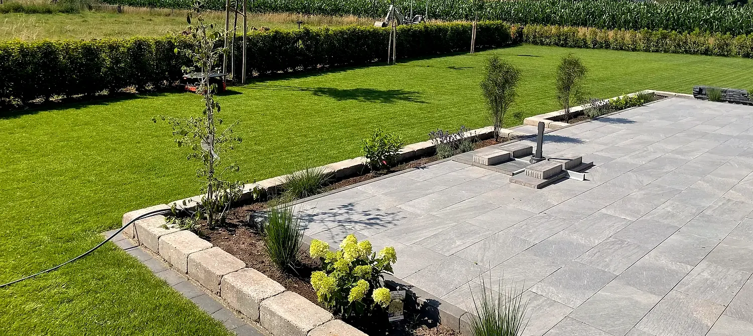Panorama einer angelegten Gartenanlage mit Pflasterterrasse und Randbepflanzung